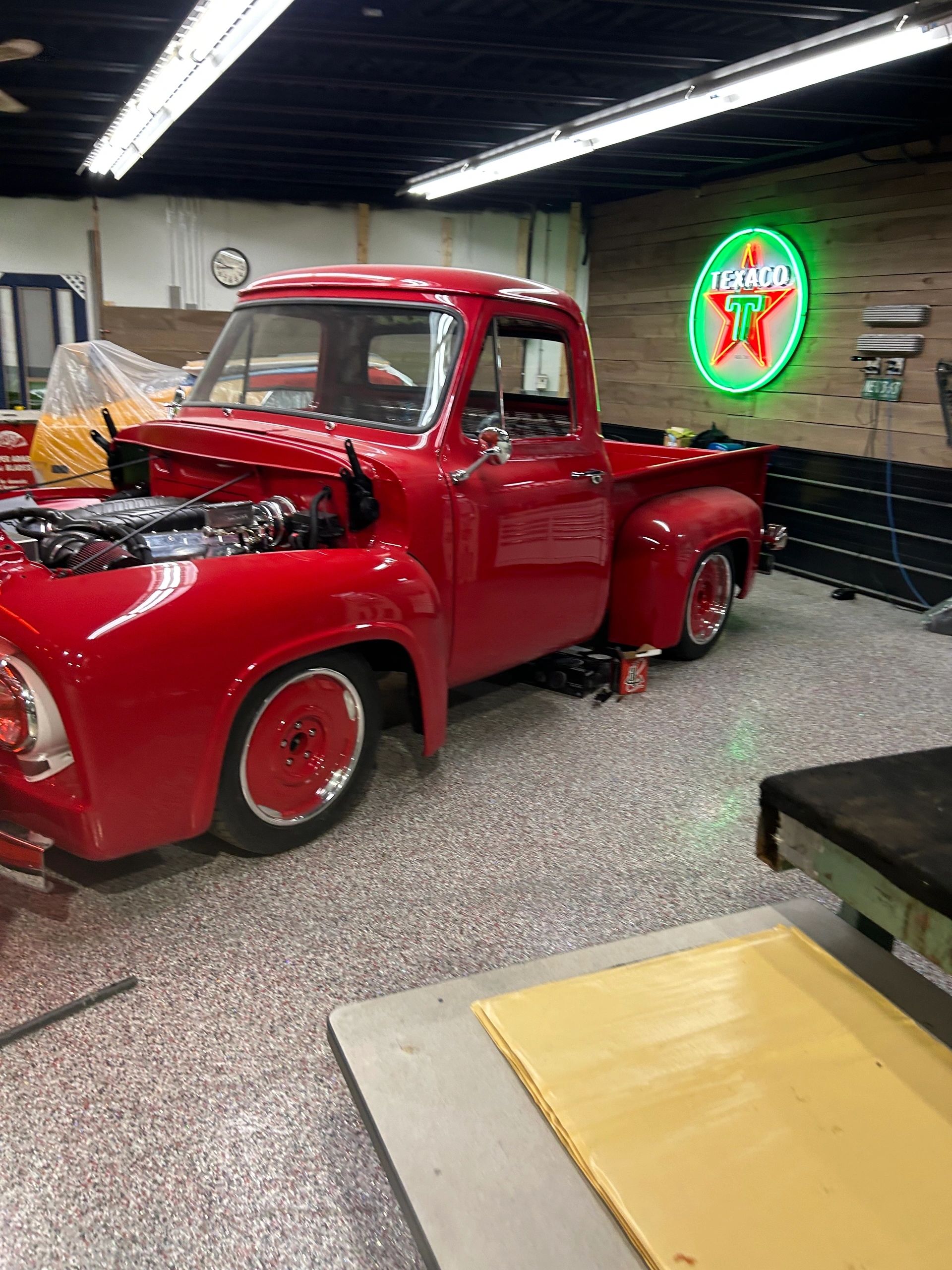 Red 1950s stepside pickup with the hood up under the Texaco neon in the 2240 bay