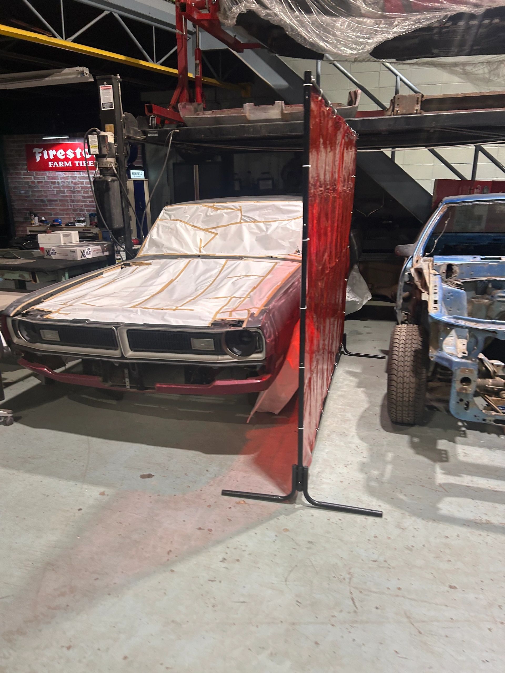 A covered classic and a masked coupe sharing a bay at 2240 Speed Shop in Edmonton