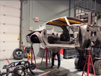 Bare custom truck body mounted high on stands during a full shop build