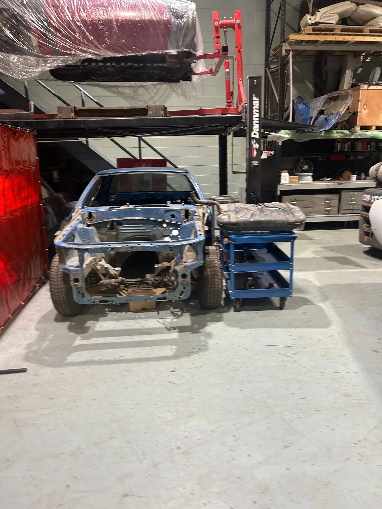 Stripped blue project car body shell during rust repair and metalwork in Edmonton