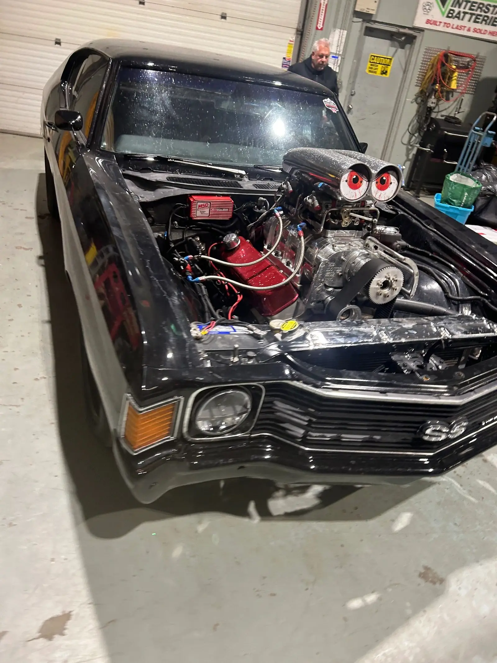 Black muscle car with exposed air intake during an engine swap at 2240 Speed Shop Edmonton